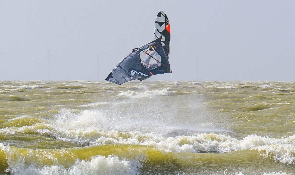 Windsurfer, hoge sprong, zwart zeil, bruin water, ijselmeer, storm achtig weer
